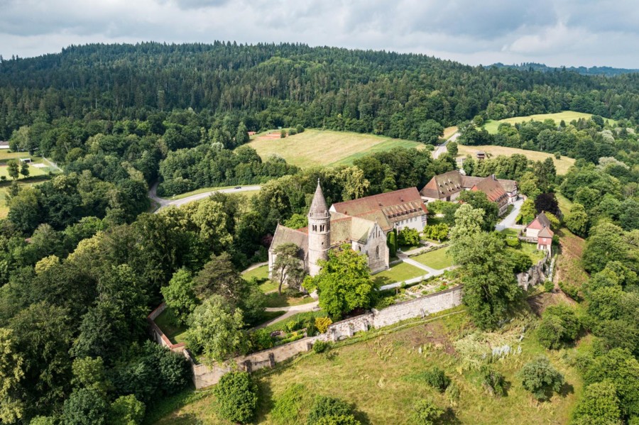 Das Bild zeigt eine Klosteranlage inmitten von Wäldern und grünen Wiesen.