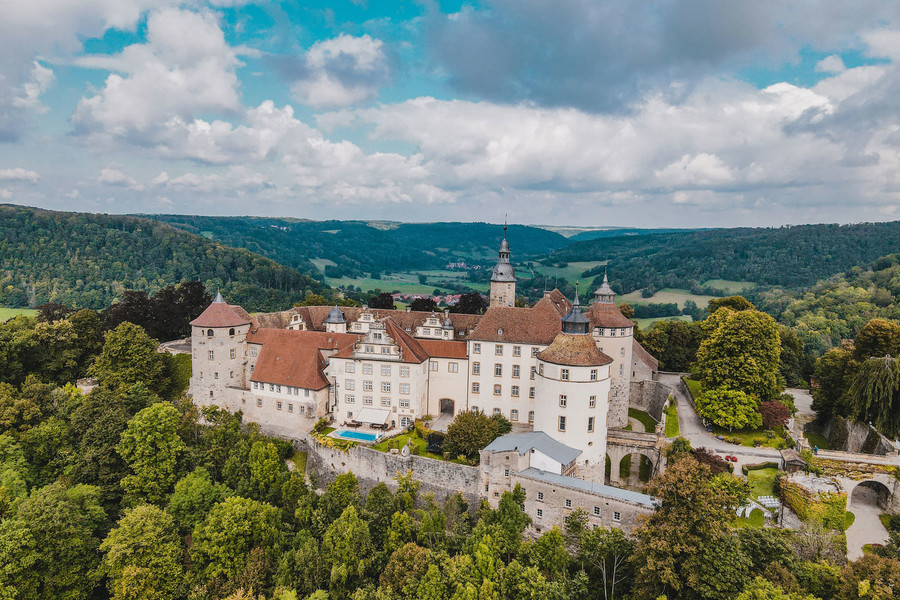 Ausblick auf Schloss Langenburg und Umgebung. Um das Schloss sind Wälder und einige Berge.