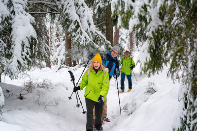 Drei Personen beim Schneeschuhwandern im dicht verschneiten Schwarzwald.